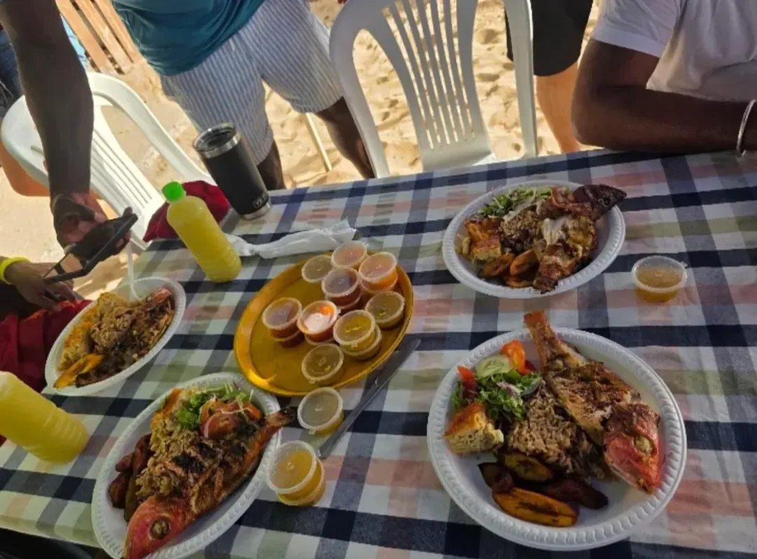 Plates of grilled fish with rice, salad and fried plantain by the beach